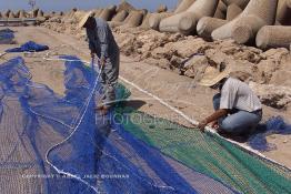 Image du Maroc Professionnelle de  Des ouvriers s'activent à réparer leurs filets de pêches au port de Laayoune, située à quelque kilomètre de la ville de Laayoune capitale du Sahara marocain, Vendredi 21 Septembre 2001. (Photo / Abdeljalil Bounhar) 